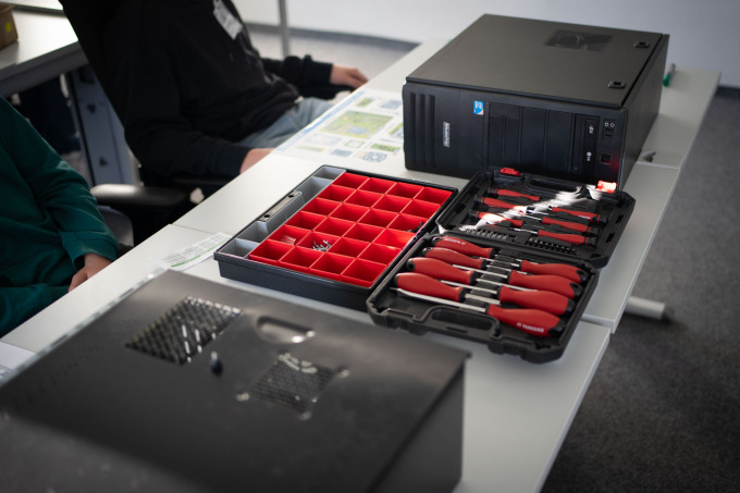 Auf einem Tisch der Station Hardware liegt ein Werkzeugkoffer und zwei PC-Gehäuse