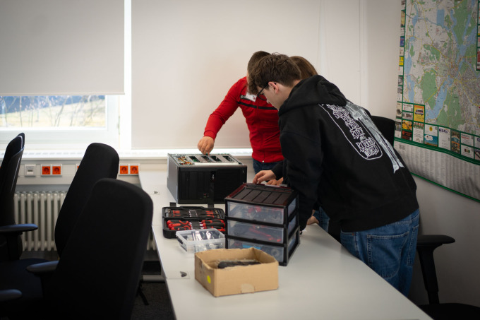 Drei Schüler begutachten die Technik auf den Tischen bei der Hardware-Station