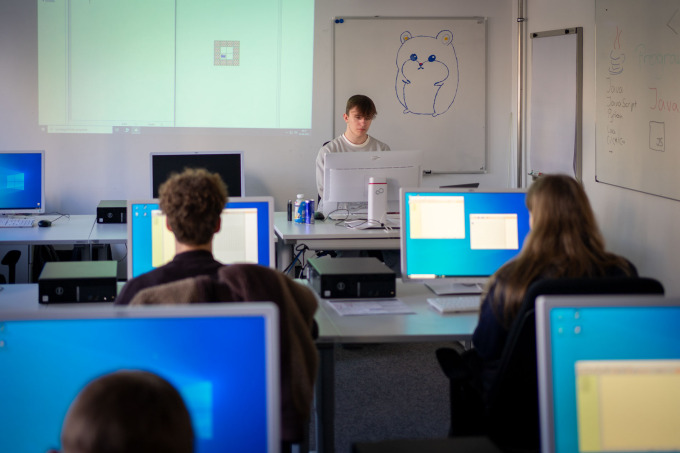Ein erster Blick in den Schulungsraum der Station Programmieren. An der Tafel ist ein Hamster angezeichnet, da ein Einstieg mit Hamster-Java gezeigt wird.